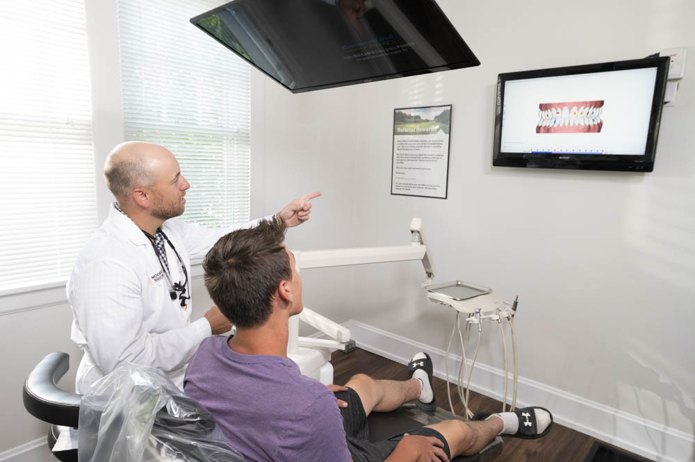 Dr. Doug Moorehead points to a monitor while in a consultation with a dental patient