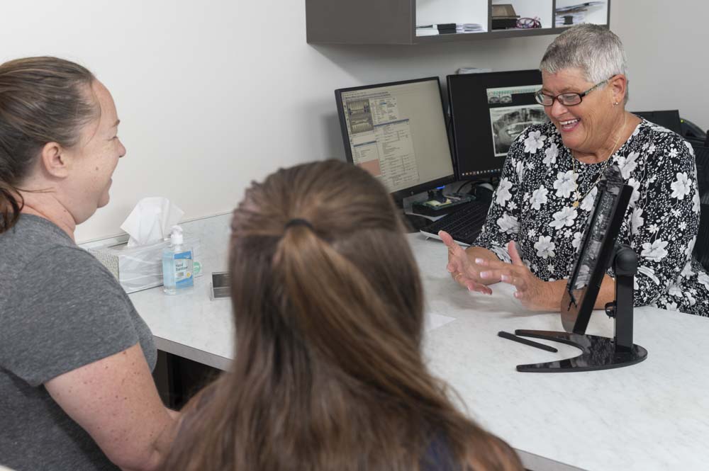 The office manager at Moorehead Dentistry speaks to dental patients during a consultation