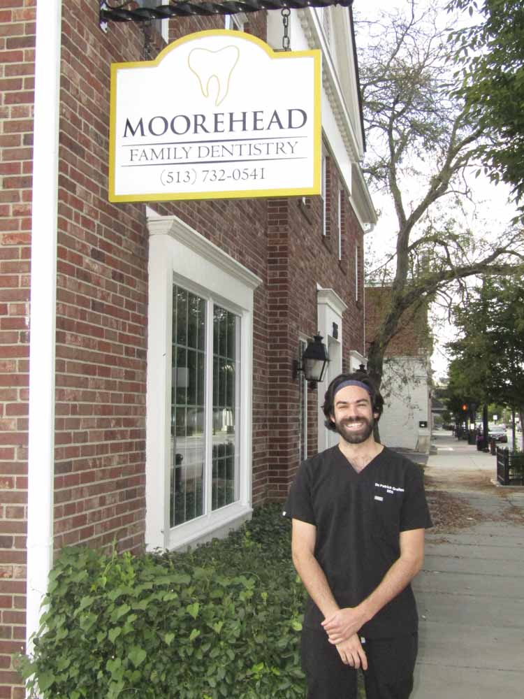 Dr. Pat Greitzer smiling under a Moorehead Dentistry sign