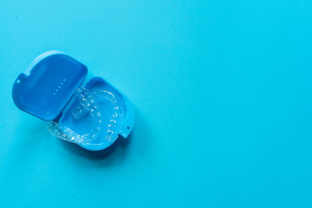 Invisalign clear aligners in a blue container on a blue background